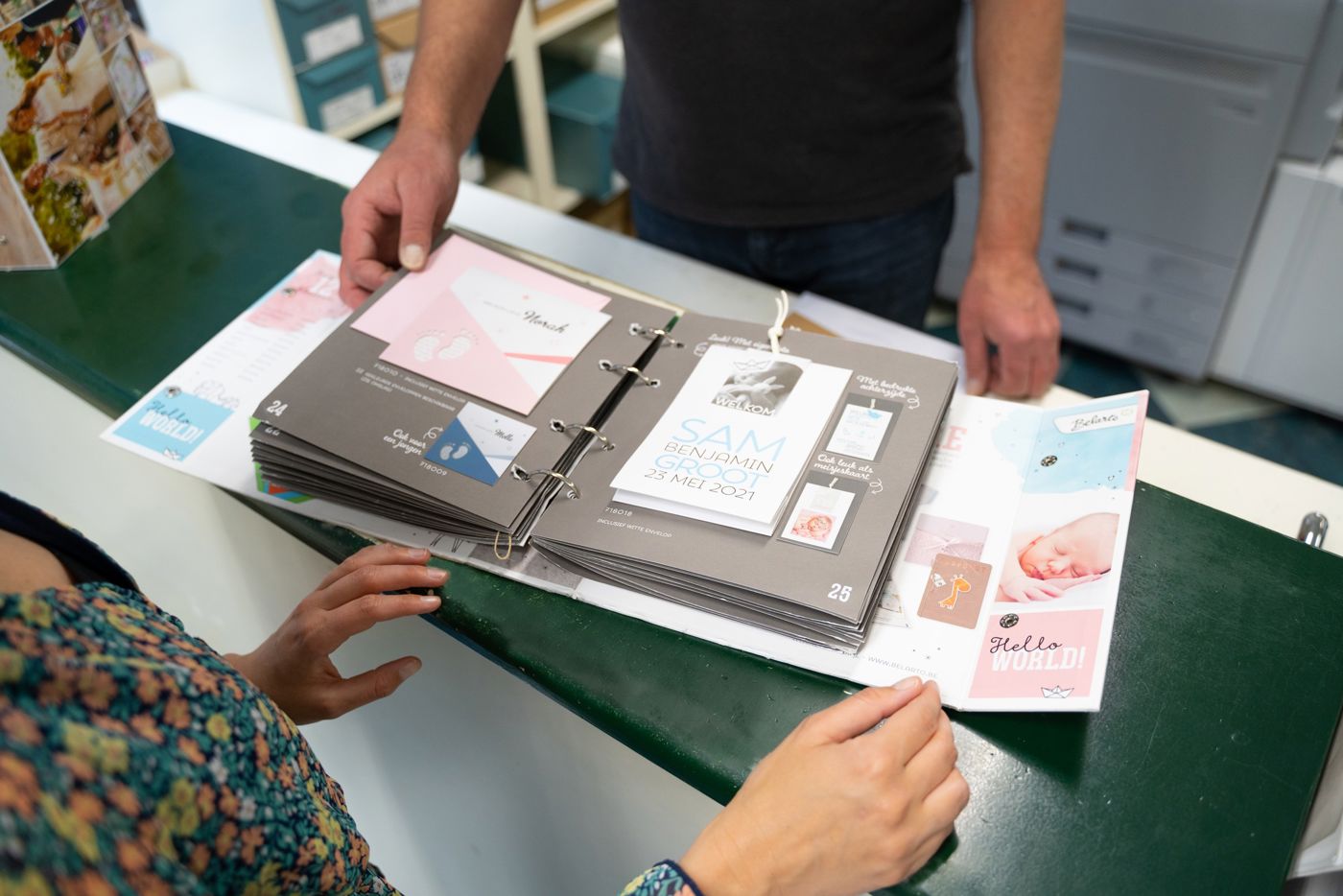 Klant achter balie in Drukkerij Zaansprint die door inspiratie boeken aan het bladeren is