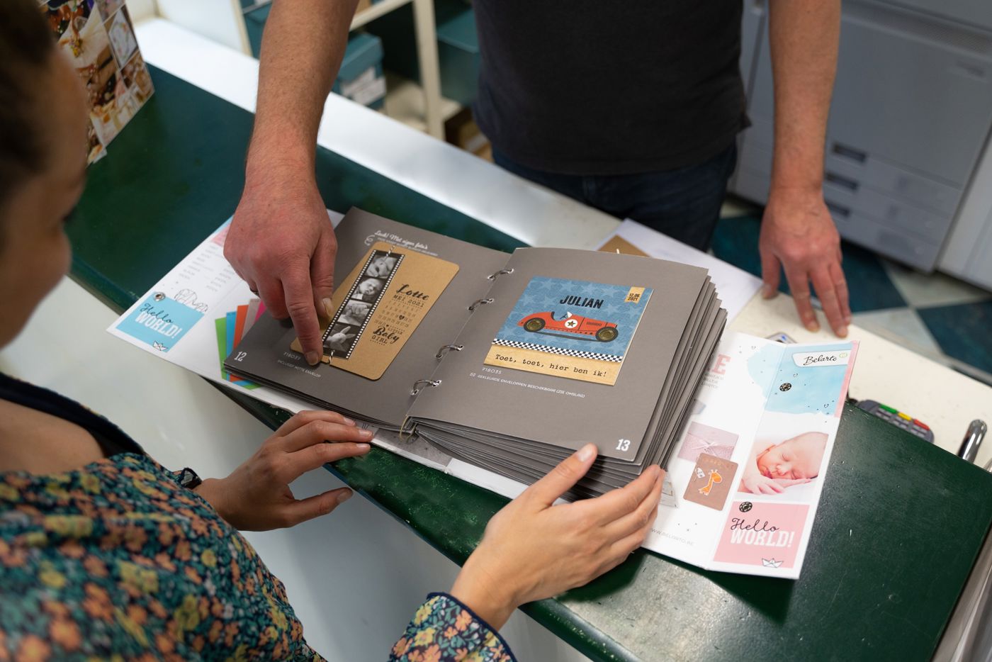 Klant achter balie in Drukkerij Zaansprint die door inspiratie boeken aan het bladeren is