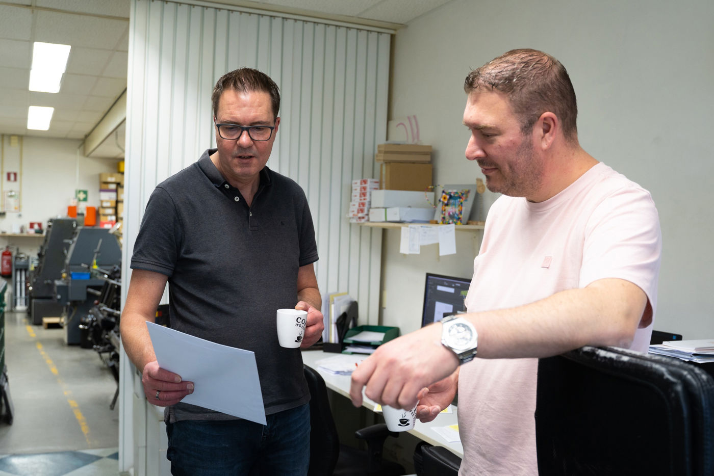 Fred en Tjeerd die samen naar een papier kijken en praten Fred en Tjeerd die samen naar een papier kijken en praten